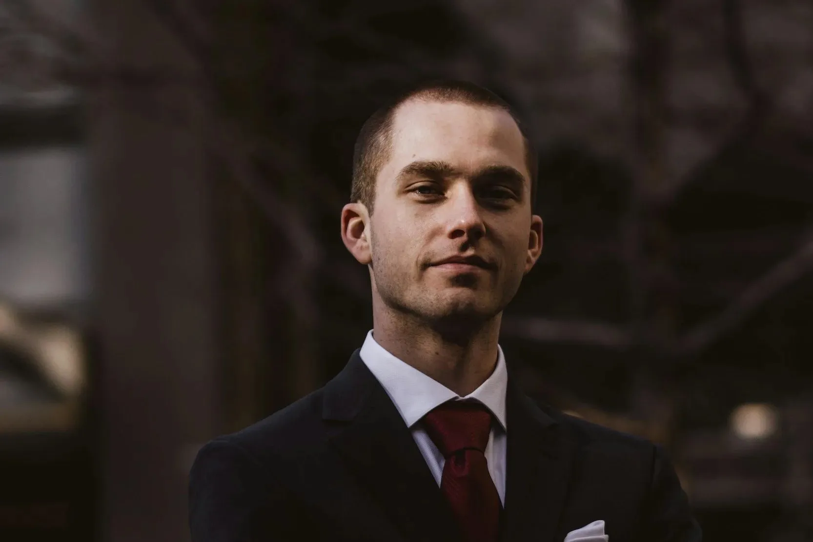A man in a dark suit and tie standing outdoors