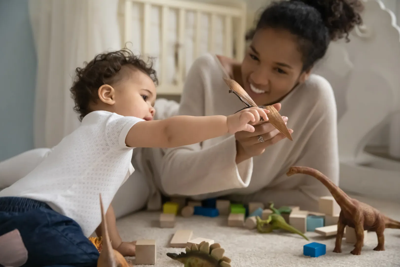 A nanny playing with a toddler on the floor